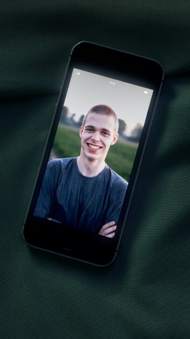 Smartphone op een bed met een achtergrondbeeld van Glenn. Een notificatie van enkele gemiste oproepen.